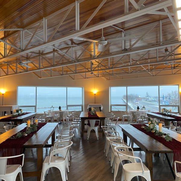 COHO Pizza & Wine Bar dining room with long wooden tables, white chairs, and lake views.