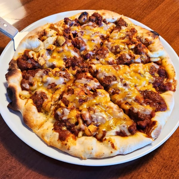 COHO Pizza's chili mac pizza, topped with ground meat, macaroni, and melted cheese.